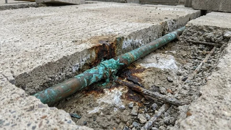 Cross-section showing corroded copper pipe embedded in a concrete slab